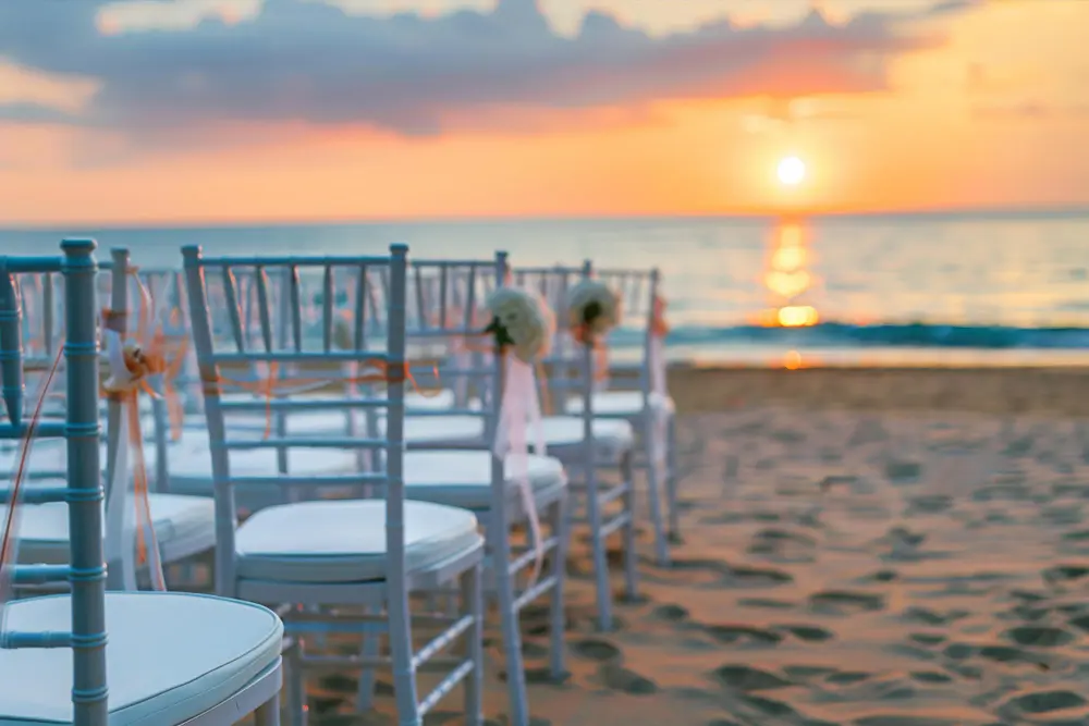 Rows of white chairs set up on the sandy beach at Rancho Santana, overlooking the Pacific Ocean with a breathtaking sunset in the background, perfect for a luxury destination wedding in Nicaragua.