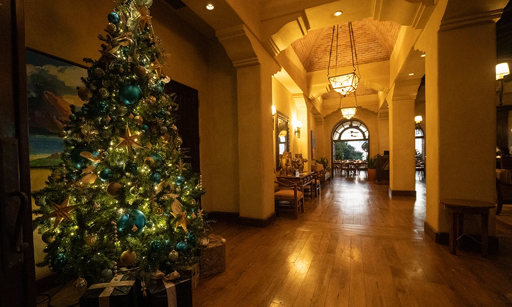 Christmas tree decorated with blue and gold ornaments in the warmly lit lobby of Rancho Santana, creating a festive holiday ambiance.