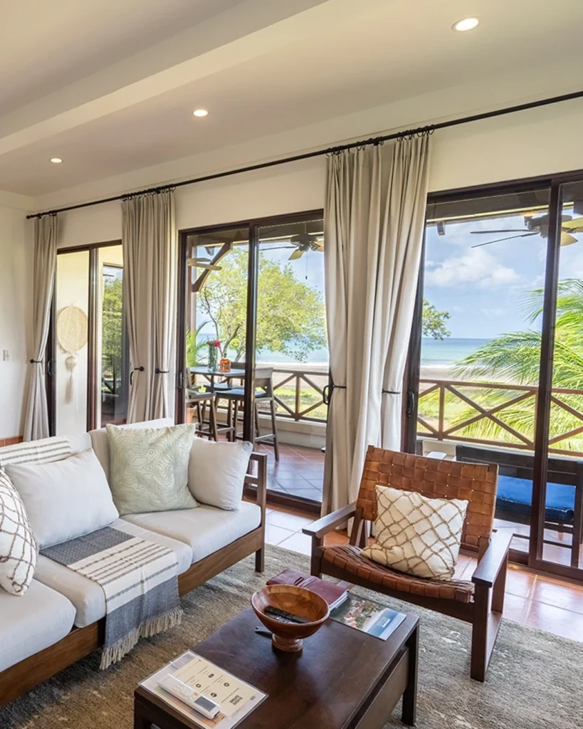 Bright and inviting living room in Puerta del Mar Villa rental at Rancho Santana, featuring cozy seating, large windows with ocean views, and access to a beachfront terrace.