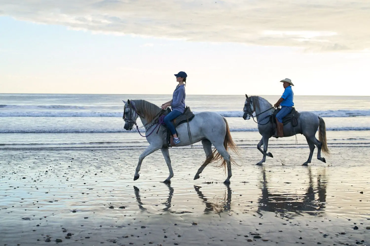 Two people horseback riding along the shoreline at Rancho Santana during sunset, one of the signature outdoor activities offered at the resort.